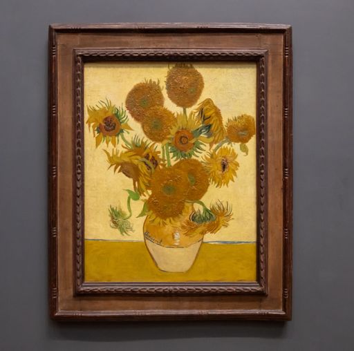 A close-up view of a framed painting of sunflowers by Vincent van Gogh in a museum