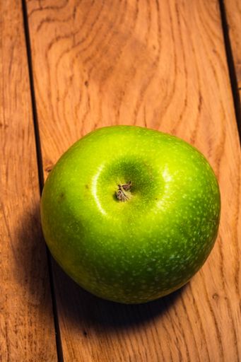 A single green juicy green apple on a wooden background
