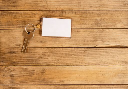 A top view of a key with a keychain on wooden background