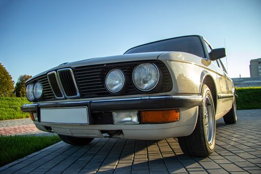 The closeup shot of the round headlights of a white vintage classic car