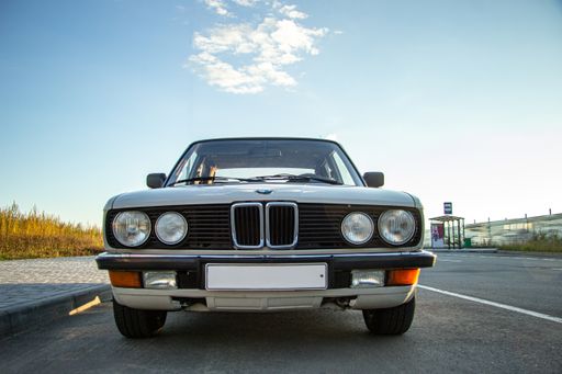 A beautiful shot of a white vintage classic car with round headlights in the road
