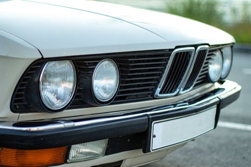 The closeup shot of the round headlights of a white vintage classic car