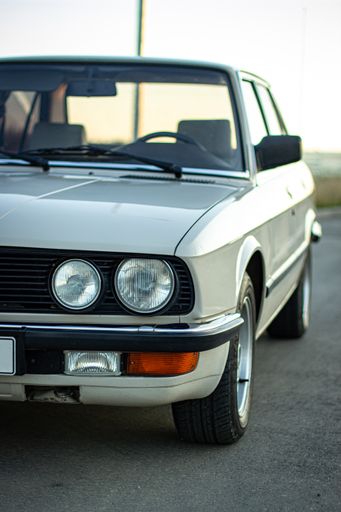 A beautiful shot of a white vintage classic car with round headlights in the road