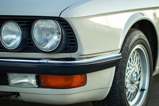 The closeup shot of the round headlights of a white vintage classic car