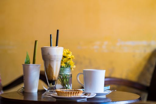 A closeup shot of iced coffee, pastry and a cup of hot tea in a cafe