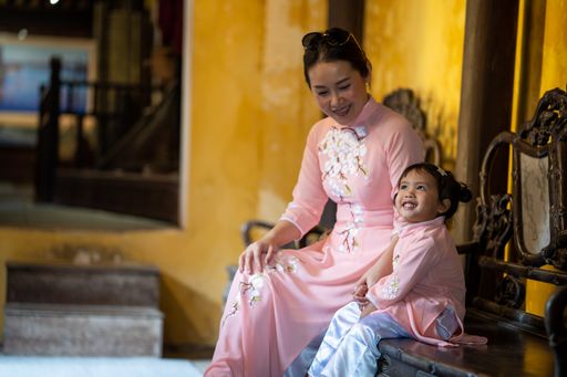 A beautiful Asian mother and daughter wearing traditional dress sitting outdoors