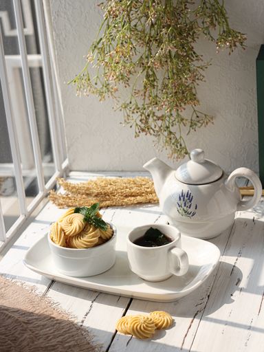 A vertical shot of meringue, a cup of coffee, a pot, and decorations on a white wooden table