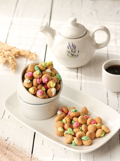 A vertical shot of biscuits on a plate, a cup of coffee, and a pot on a white wooden table