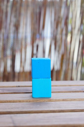 A vertical closeup shot of a two blue wooden toy blocks stacked on top of each other on a wooden table