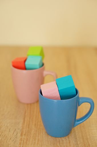 A vertical shot of colorful wooden square toys in the cups