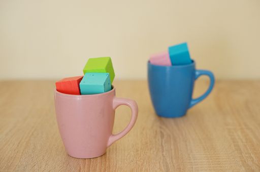 A closeup shot of wooden toy blocks in two coffee cups on a wooden table