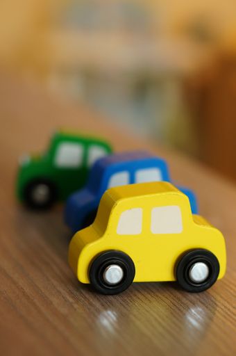 A selective focus shot of a yellow wooden toy car on a wooden table