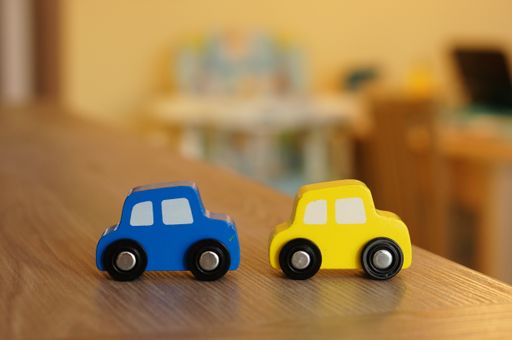 A selective focus shot of colorful wooden toy cars on a wooden surface