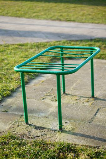 A vertical shot of an old green metal bench at the park