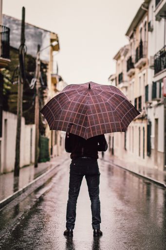 A beautiful shot of a person wearing black pants holding umbrella on a road