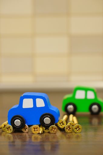 A vertical shot of a blue wooden toy car on nails