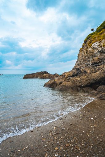 A natural view of a sandy beach on an island under a cloudy day in the summertime