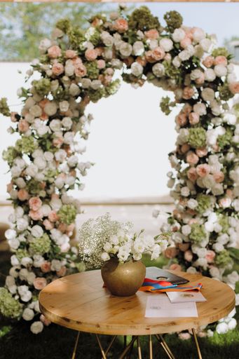 A beautifully decorated wedding arch with flowers and a wooden table