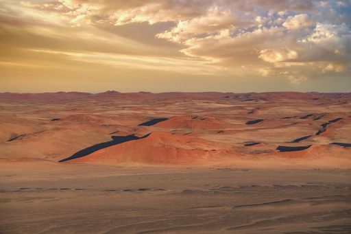 A stunning desert landscape with sand dunes under a dramatic sky at sunset