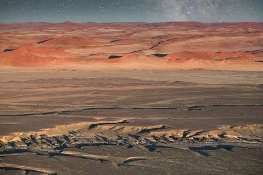 Beautiful desert landscape with red sand dunes under a starry night sky in Namibia.