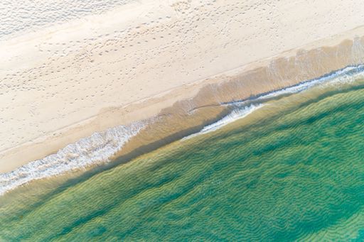 background for summer vacation concept. aerial top view with drone of the waves of a turquoise sea on the shore of a beach.