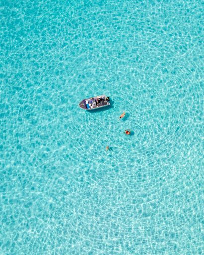 Aerial view of a boat and swimmers in crystal clear turquoise water