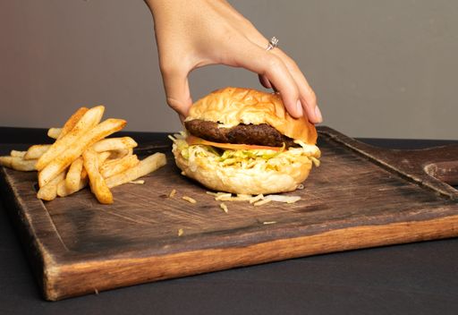 A hand opening a burger to see what is inside