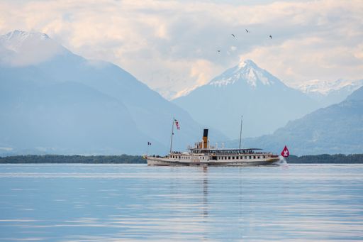 Landscape view of the CGN boat "La Suisse" on the Geneva Lake with a mountain range in the background, shot from Vevey, Vaud Switzerland