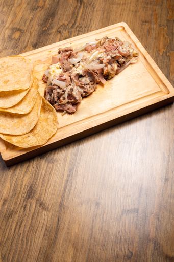 A vertical shot of cooked chopped meat with onions on a wooden board