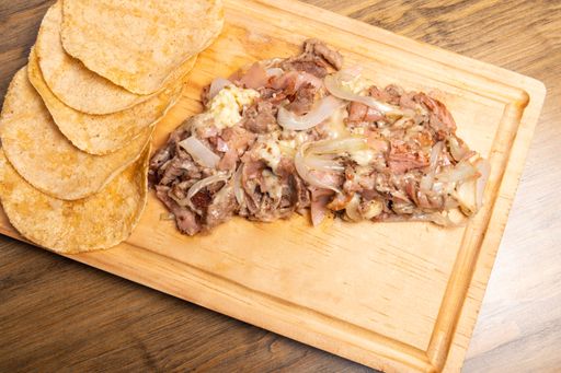 A high angle shot of cooked chopped meat with onions on a wooden board