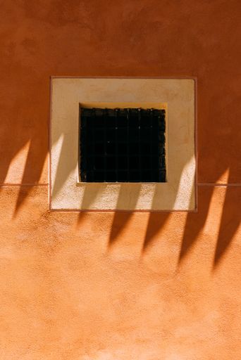 A vertical shot of a small blacked-out window on a beautiful orange building in Toledo, Spain