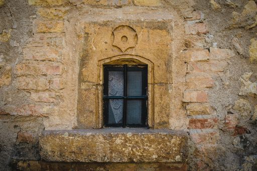 A closeup shot of a closed window on a yellow stone wall