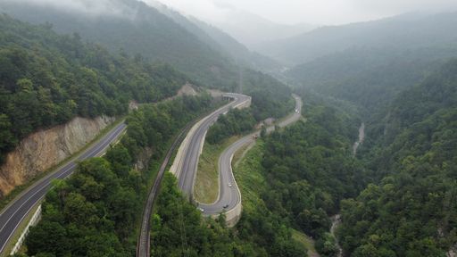 An aerial shot of a narrow winding mountain road leading to Ijevan town, Armenia on a foggy day