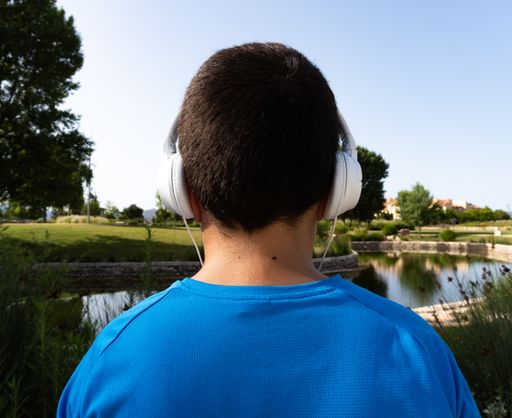 A back view of a boy with headphones spending his leisure time in the park