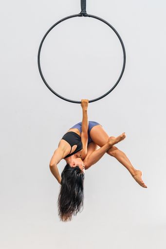 A woman gracefully performs an aerial hoop routine suspended in mid-air.