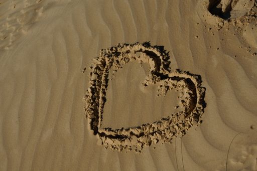 A closeup shot of a heart drawn on a sand surface