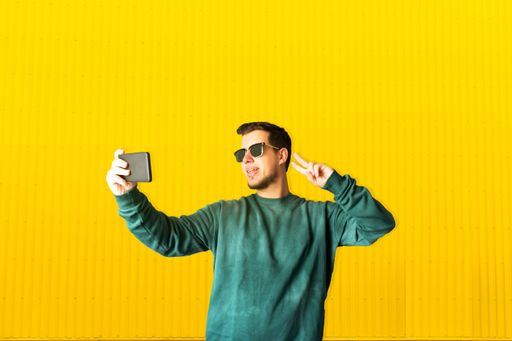 A Portrait of a smiling young man taking a selfie in the street. Communication concept.