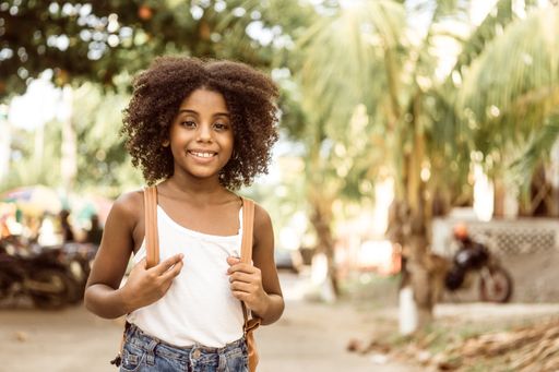 A smiling Afro-American girl holding her backpack - back to school