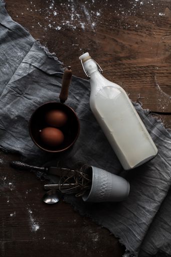 A high-angle shot of eggs, a bottle of milk and utensils for baking