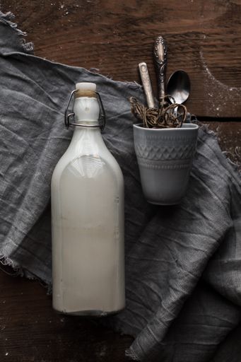 A top view shot of a bottle of milk and utensils for baking on a wooden table