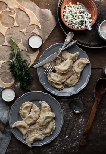 A top view of two plates of fresh dumplings on a wooden table with ingredients