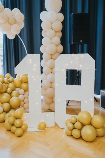 The decorative balloons and large number 18 for a birthday celebration in an indoor setting