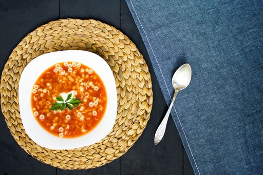 A top view of Tomato soup and spoon on blue cloth background