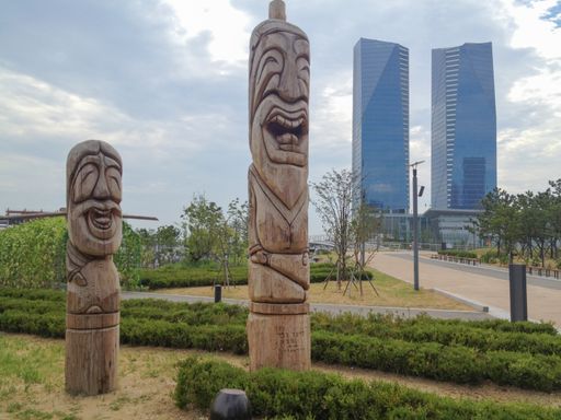 The skyline of Songdo in South Korea, wooden totem poles called jangseung in a park