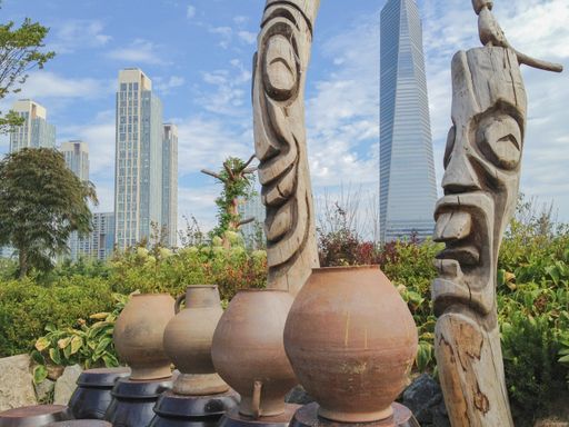 The skyline of Songdo in South Korea, wooden totem poles called jangseung in a park