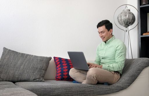A young businessman sitting on the couch with a laptop - working from home concept