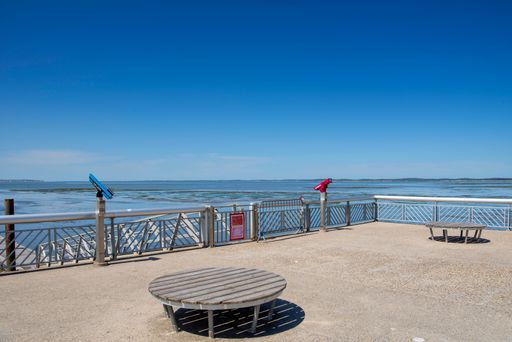 A scenic view of a waterfront observation deck with clear blue skies and distant landmasses