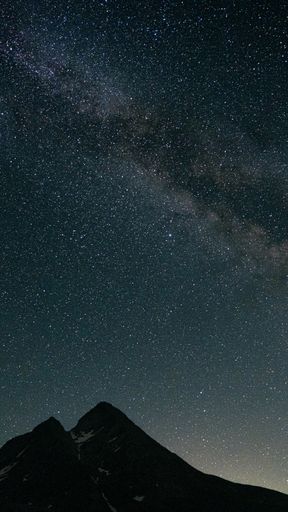 A vertical shot of a starry night sky over mountains with visible Milky Way galaxy in Riale, Verbano-Cusio-Ossola, Italy