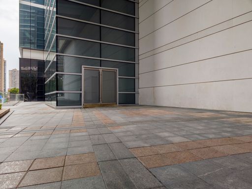 A modern glass and concrete building exterior and tiled pavement