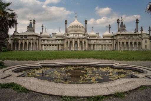 The Royal Pavilion in Brighton, England, with a reflection pond in the foreground and a partly cloudy sky